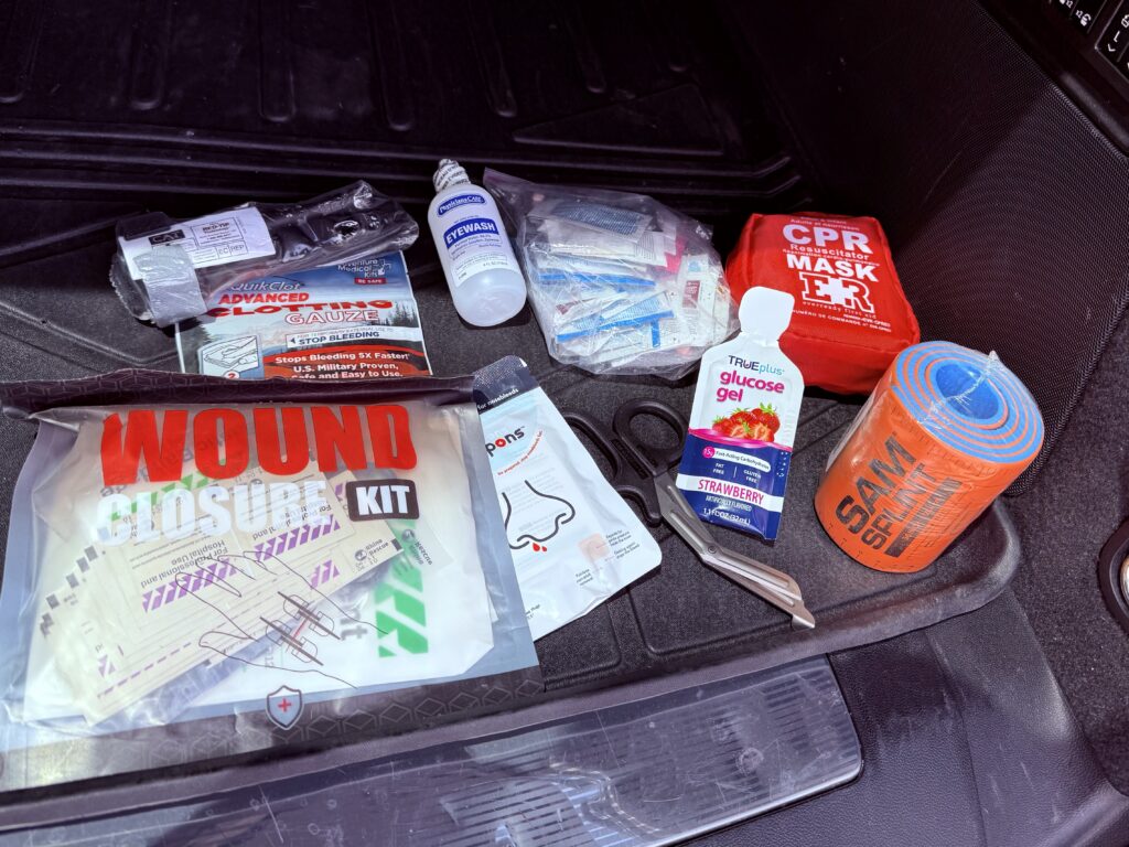 First aid kit contents including tourniquet, QuikClot gauze, CPR mask, SAM splint, and wound closure kit — Colorado Luxury Driver luxury chauffeur Denver mountain transportation